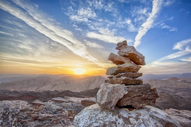 Photos d'un cairn au sommet d'une montagne avec un coucher de soleil, illustrant le succès lorsqu'on déteste son travail et qu'on passe à l'action