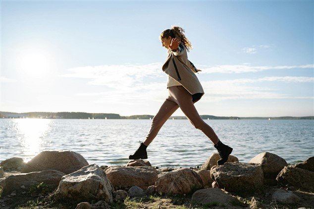 photo d'une femme marchant en équilibre sur des pierres pour illustrer la période de fin de son travail suite à un burnout, dernière épreuve avant de pouvoir rebondir avec les indemnités chômage